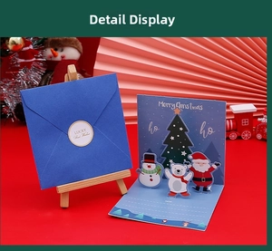 Macro view of 3D pop-up Christmas card featuring Santa Claus and snowman with envelope