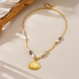 Tropical gold necklace with seashell and scallop shell pendants on a textured beige surface