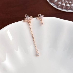 Macro shot of rose gold flower earrings with opals and asymmetrical long chain details
