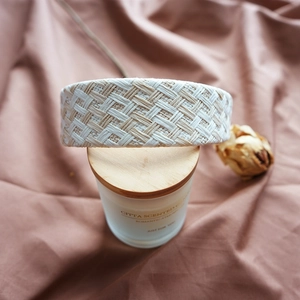 Detailed close-up of a woven beige and white raffia headband on brown pleated fabric