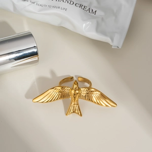 Détail d'une bague hirondelle dorée ajustable sur fond esthétique épuré