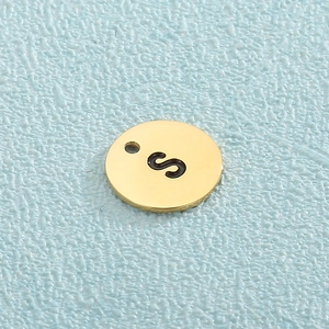 Detailed view of a gold plated titanium steel circular pendant with a black engraved letter S