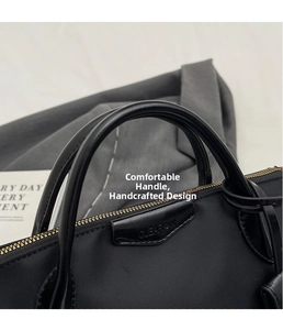 Detail of black nylon dumpling bag with gold zipper and textured leather handle