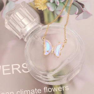 Macro detail of gradient butterfly pendant with iridescent wings on a gold chain necklace
