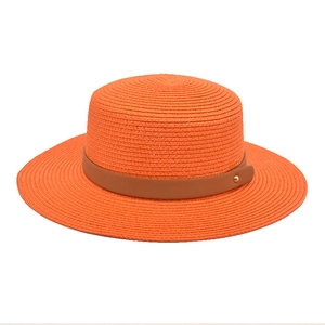 Detail of bright orange straw boater hat featuring brown leather band and gold buckle