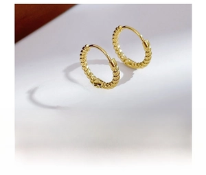 Macro shot of gold twisted rope texture on stainless steel hoop earrings with vacuum plating