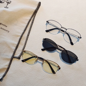 Three pairs of oval metal frame glasses in gold, silver and black colors on beige background