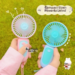 Close-up of portable mini USB hand fans in pink and blue on green grass background