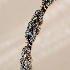 Close-up of vintage bronze headband with leaf patterns and colorful rhinestones
