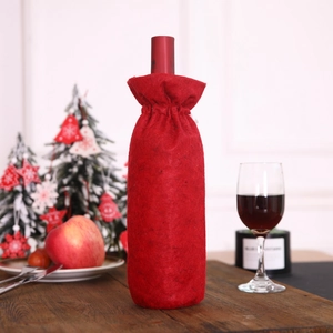 Detail of red felt Christmas wine bottle cover on a festive wooden table setting