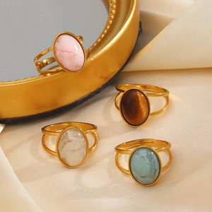 Vintage gold oval resin rings with pink, brown, white, and green stones on satin cloth