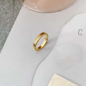 Detail of a minimalist gold-plated titanium ring featuring vertical striped textures