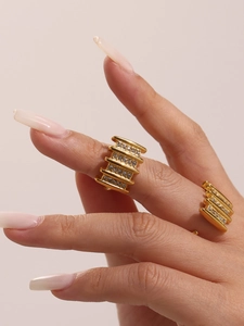Detail of multi-row gold stainless steel rings set with crystals on a hand