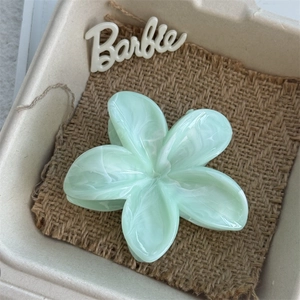 Detail of light green floral hair claw clip with marble texture on brown burlap fabric