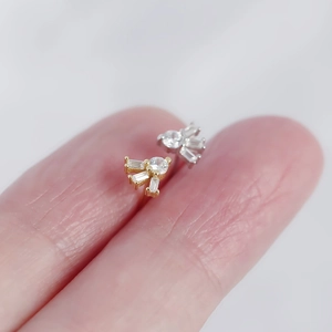 Macro shot of S925 silver square zircon stud earrings in gold and silver on a fingertip