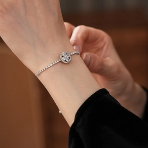 Detailed macro view of the rotating zircon clover charm and diamond chain on the wrist