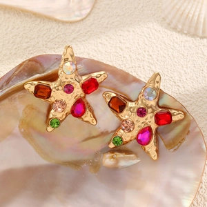 Golden starfish earrings with multicolored rhinestones on a sea shell background