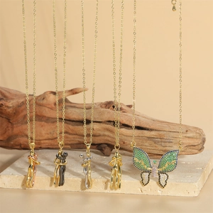 Collection of butterfly and hug pendants in gold and silver hanging over stone