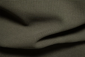 Macro shot of olive green waffle knit fabric texture on a men's stand collar jacket