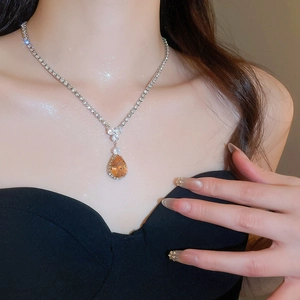Macro shot of silver necklace with champagne teardrop zircon pendant on a model