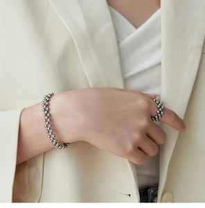 Close-up of model wearing silver triple-row beaded bracelet and matching ball ring set