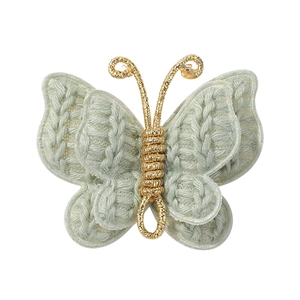 Macro detail of hand-knitted mint green yarn butterfly with golden metallic body