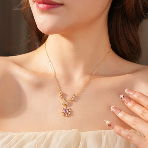 Close-up of vintage gold necklace featuring a pink oval zircon stone on a model's neck