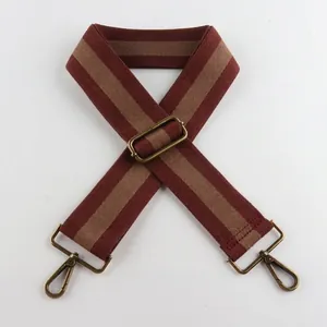 Close-up of vintage brown and beige striped wide canvas bag strap with bronze metal clips