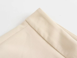Macro detail of beige slim-fit trousers showing precision double-folded stitching and texture