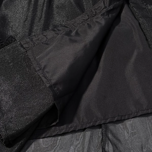 Detailed view of shimmering black mesh fabric layered over a smooth inner lining