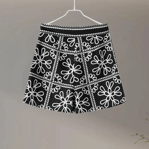 Modern black floral print high-waisted shorts with lace stitching on neutral background