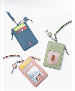 Detail of lychee pattern leather card holders in peacock blue, green and pink with lanyards