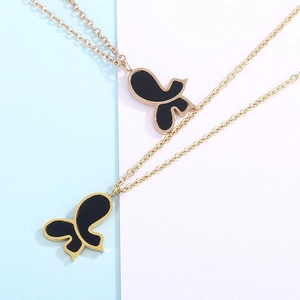Detail of asymmetric butterfly pendant in gold and black on a dual-tone background