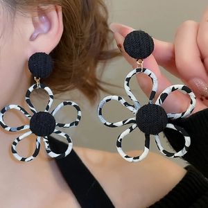 Gros plan sur des boucles d'oreilles fleurs en tissu léopard avec détails ajourés chics