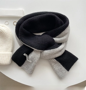 Flat lay of thick color-block knit scarf with black and grey ribbed texture and warm feel