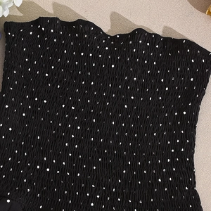 Detail eines schwarzen gesmokten Bandeau-Tops mit weißen Punkten und elastischer Textur