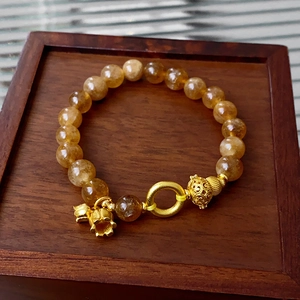 Detailed close-up of amber crystal beaded bracelet with gold flower charms on a wooden tray