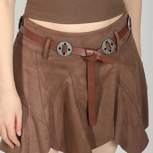Detail of a brown suede skirt featuring a leather belt with decorative silver round buckles