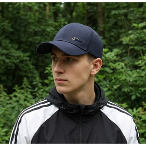Detail of navy blue cotton baseball cap with Sport embroidery in a forest setting