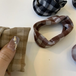 Detail of plaid patterned scrunchies in brown and grey fabric with elastic design