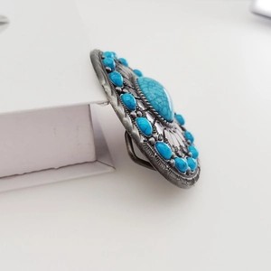 Close-up of vintage silver oval belt buckle with decorative blue turquoise stones