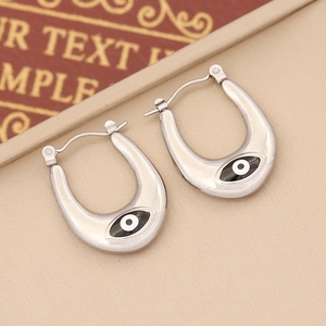 Macro view of silver U-shaped stainless steel earrings with enamel evil eye detail
