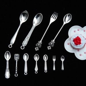 Detailed view of silver miniature dollhouse cutlery set with vintage spoons and forks