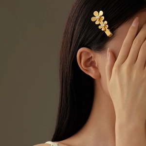 Elegant gold flower hair clip with zircon petals worn by a model on grey background