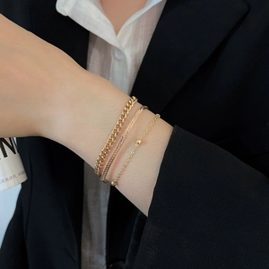 Close-up of a three-piece gold snake chain bracelet set on a model wrist with a suit