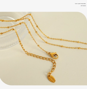 Detailed close-up of the gold stainless steel necklace chain with lobster clasp and tag