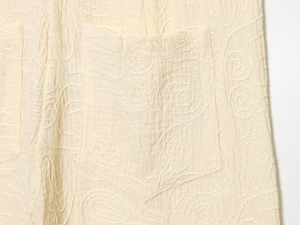 Gros plan sur la broderie florale et la poche sur tissu coton-lin blanc cassé