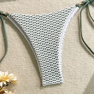 Detail of white crochet bikini bottom featuring gold rings and pearl bead accents