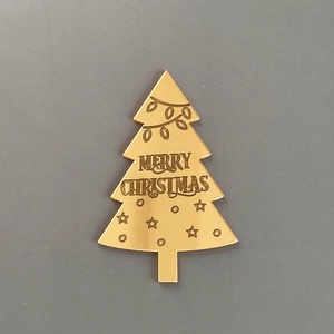 Détail de cake topper sapin de noël en acrylique doré, vue rapprochée design gravé.