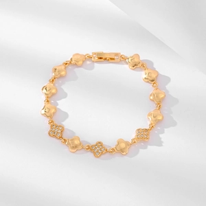 Detail eines vergoldeten Kleeblatt-Armbands mit funkelnden Zirkonia-Steinen für Damen